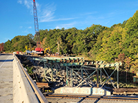 Distant view of bridge beams with trees in background.